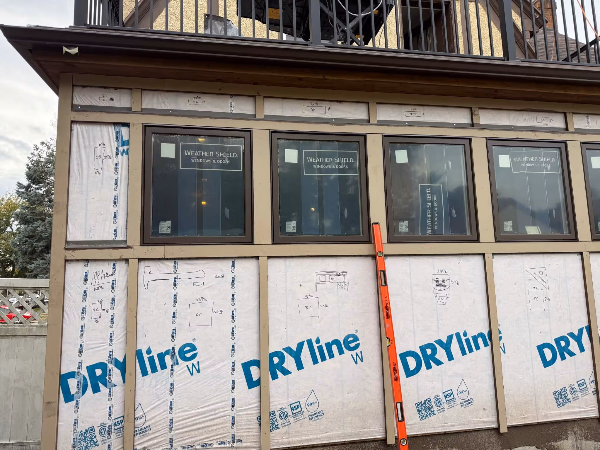 Construction of exterior wall with four Weather Shield windows installed and DRYline house wrap applied.